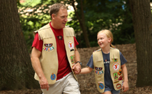 A father and son dressed as boy scouts in the woods
